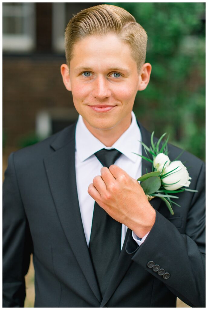 Groom smiling while fixing black tie