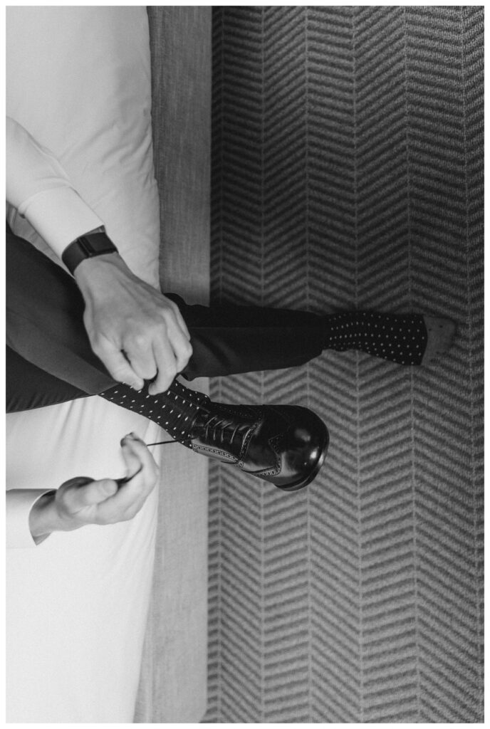 Groom tying his formal shoes in groom hotel suite