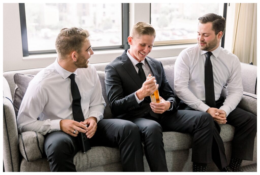 Groom pulling whiskey from jacket to enjoy with groomsmen